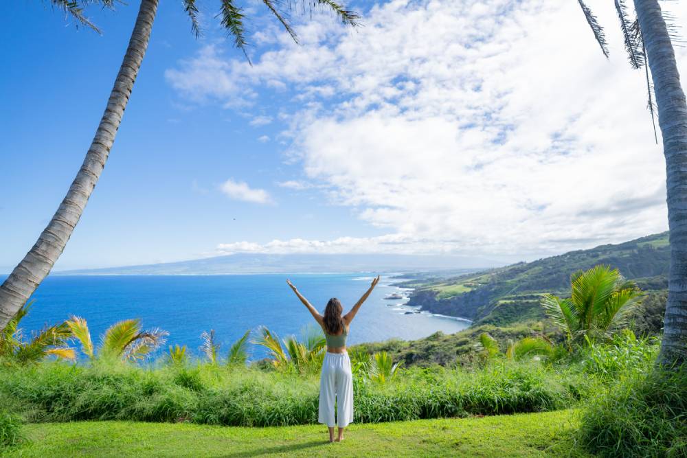 Woman with arms in V overlooking Pacific Maui
