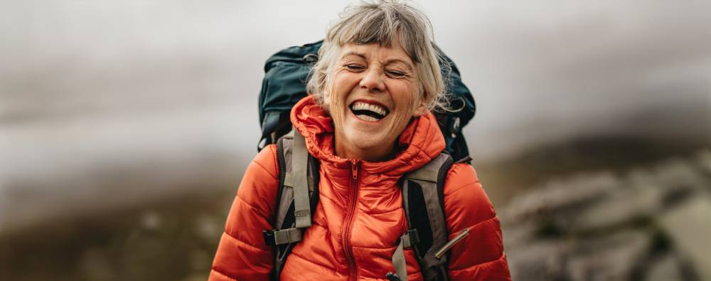 Laughing mature solo female traveler on hike
