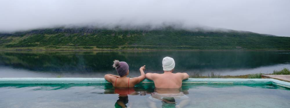 Couple unwind in hot springs, Westfjords Iceland