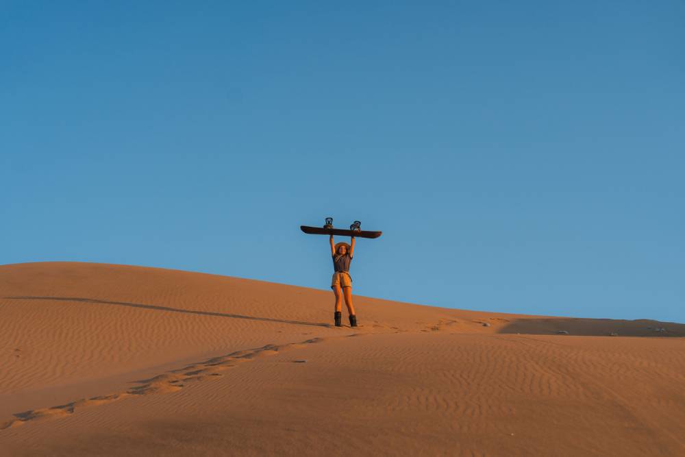 Woman sandboarding in desert in Peru at sunset