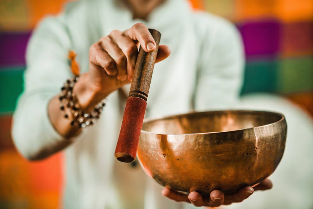 Midsection of sound bath practitioner playing singing bowl