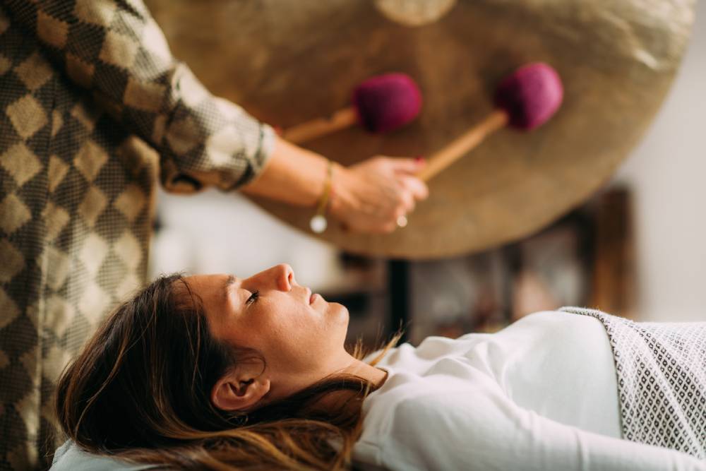 Practitioner playing gong in sound bath therapy