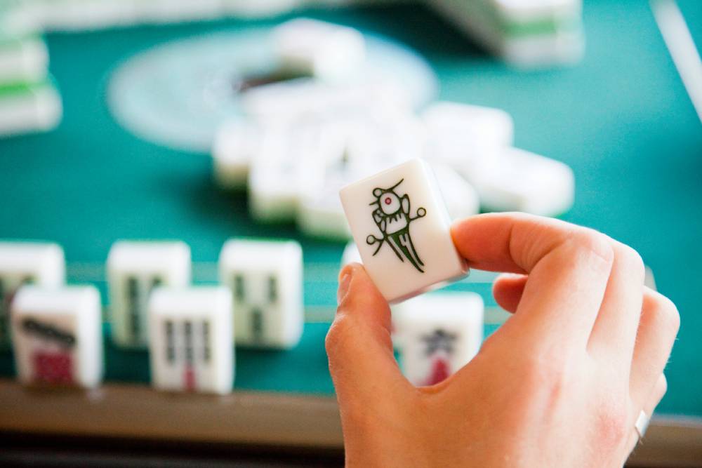 Close up of mahjong tile in player's hand.