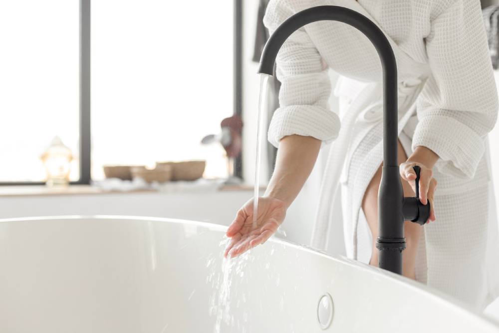 Woman turning on the water of bathtub at home
