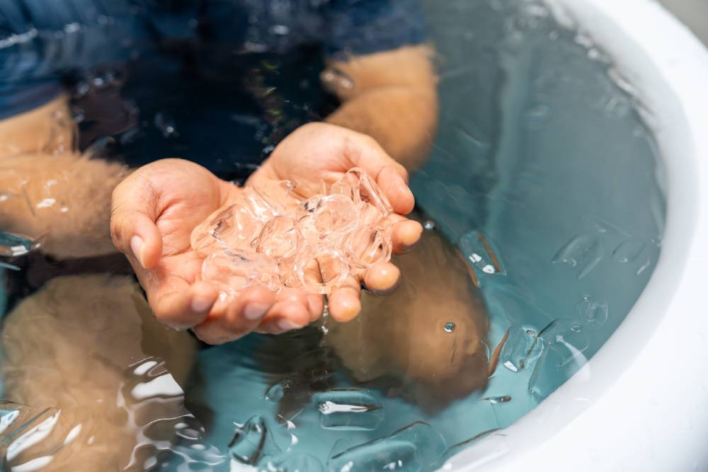 Man practices cold therapy and ice bathing in inflatable tub