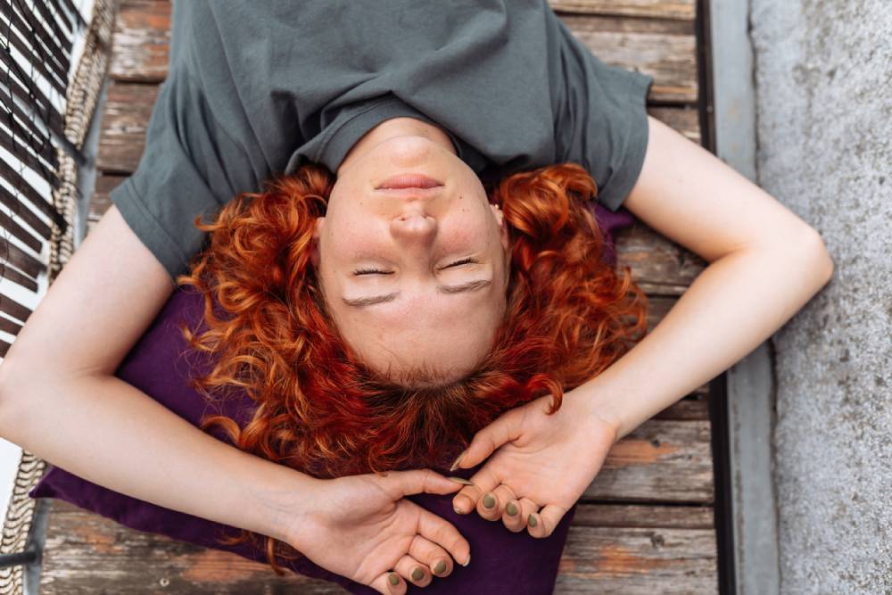 Red-haired woman lying on wooden balcony doing nothing