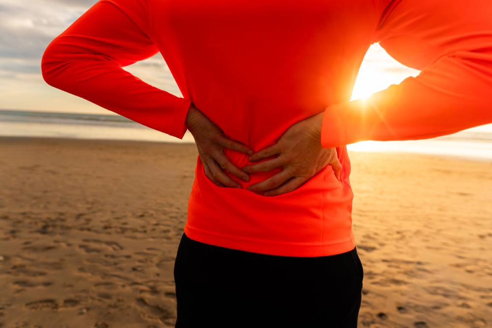 Backside of runner on beach admiring sunset