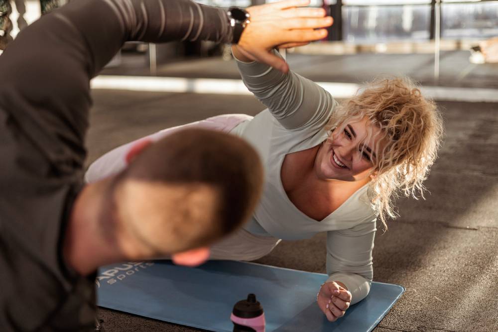 Overweight woman celebrating progress with trainer