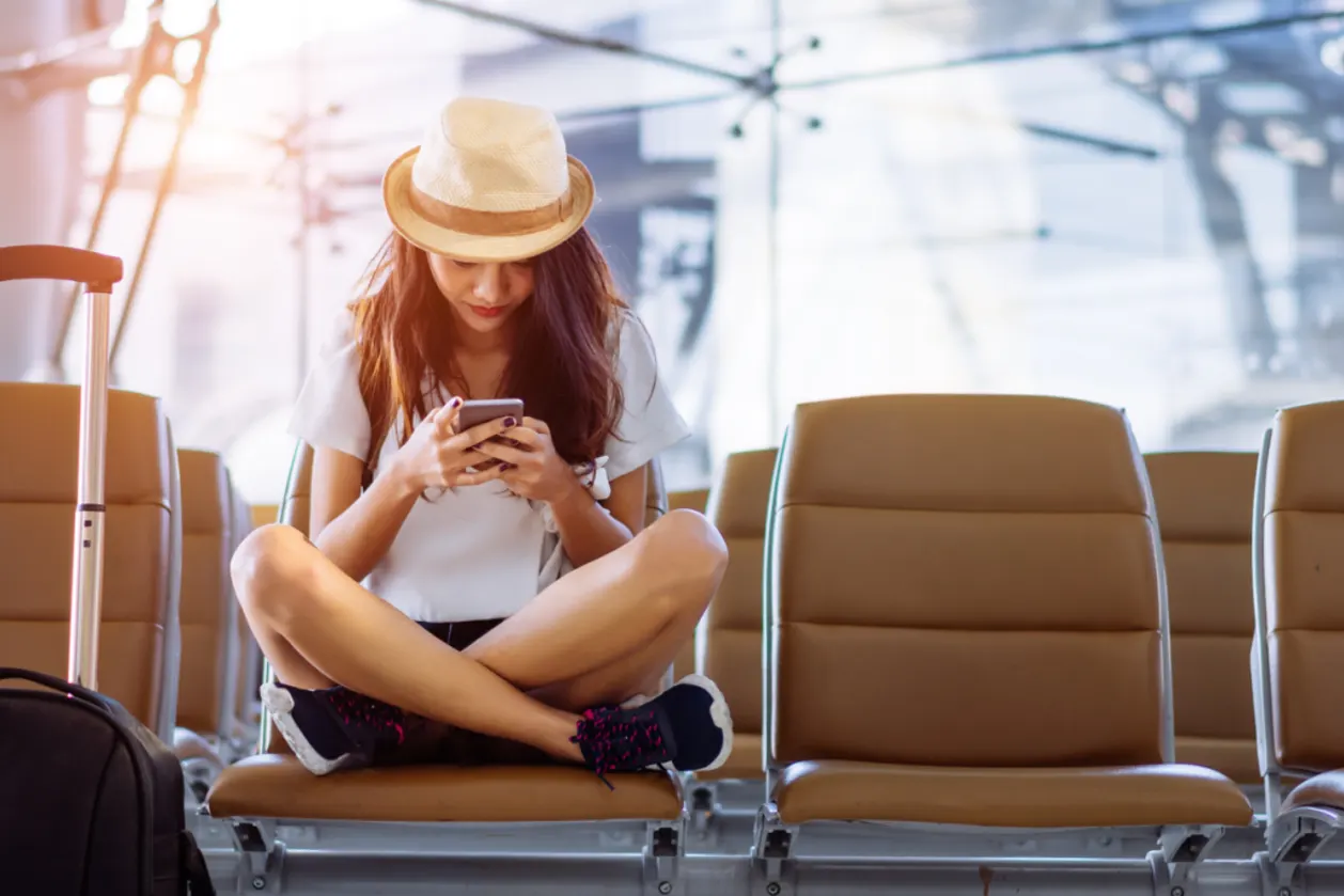 woman using smartphone while waiting for flight