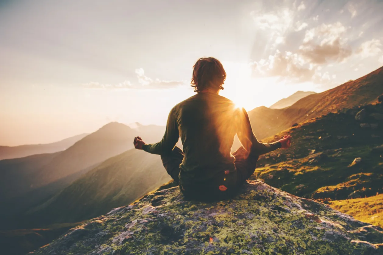 open your heart chakra-man-meditating-at-sunset-mountains