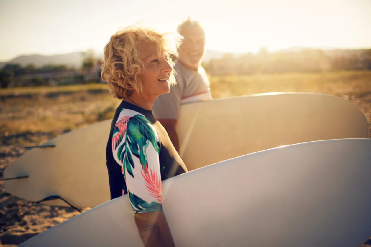 benefits of surfing mature couple holding surfboards