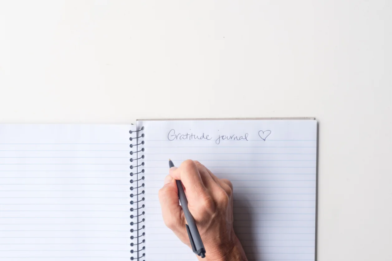 woman's hand writing in gratitude journal as a daily ritual