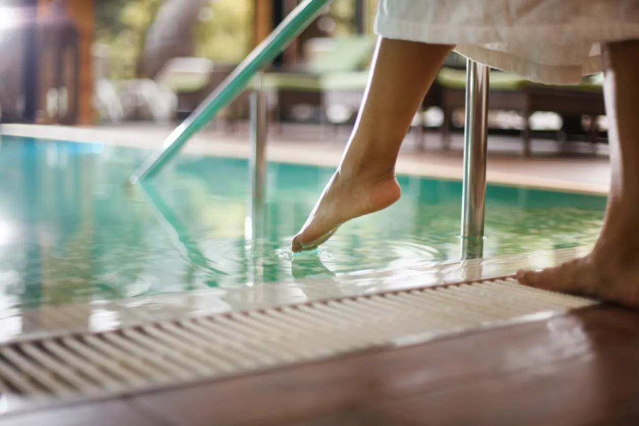 woman in bathrobe dipping toes into pool spa resorts scene