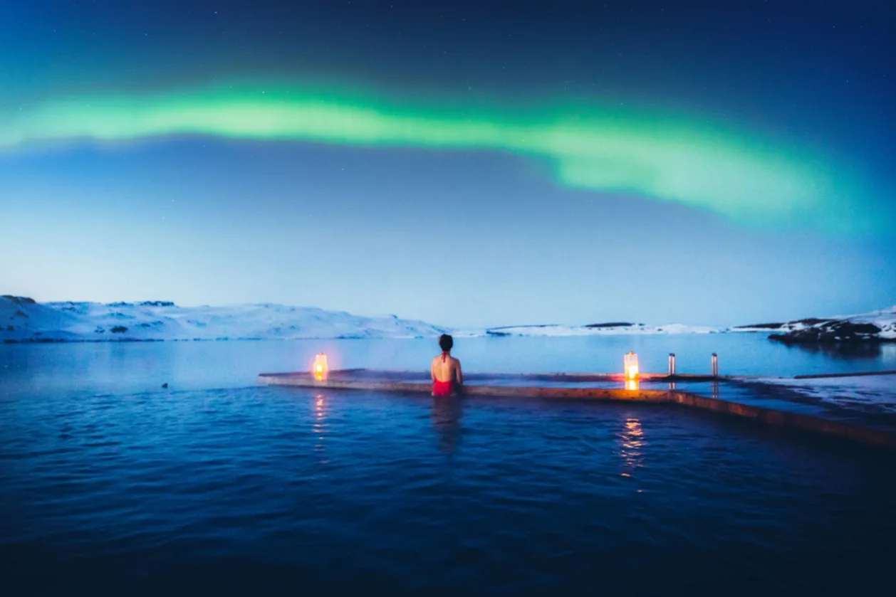 woman in lake watching northern lights as part of noctotourism wellness travel trend of 2025