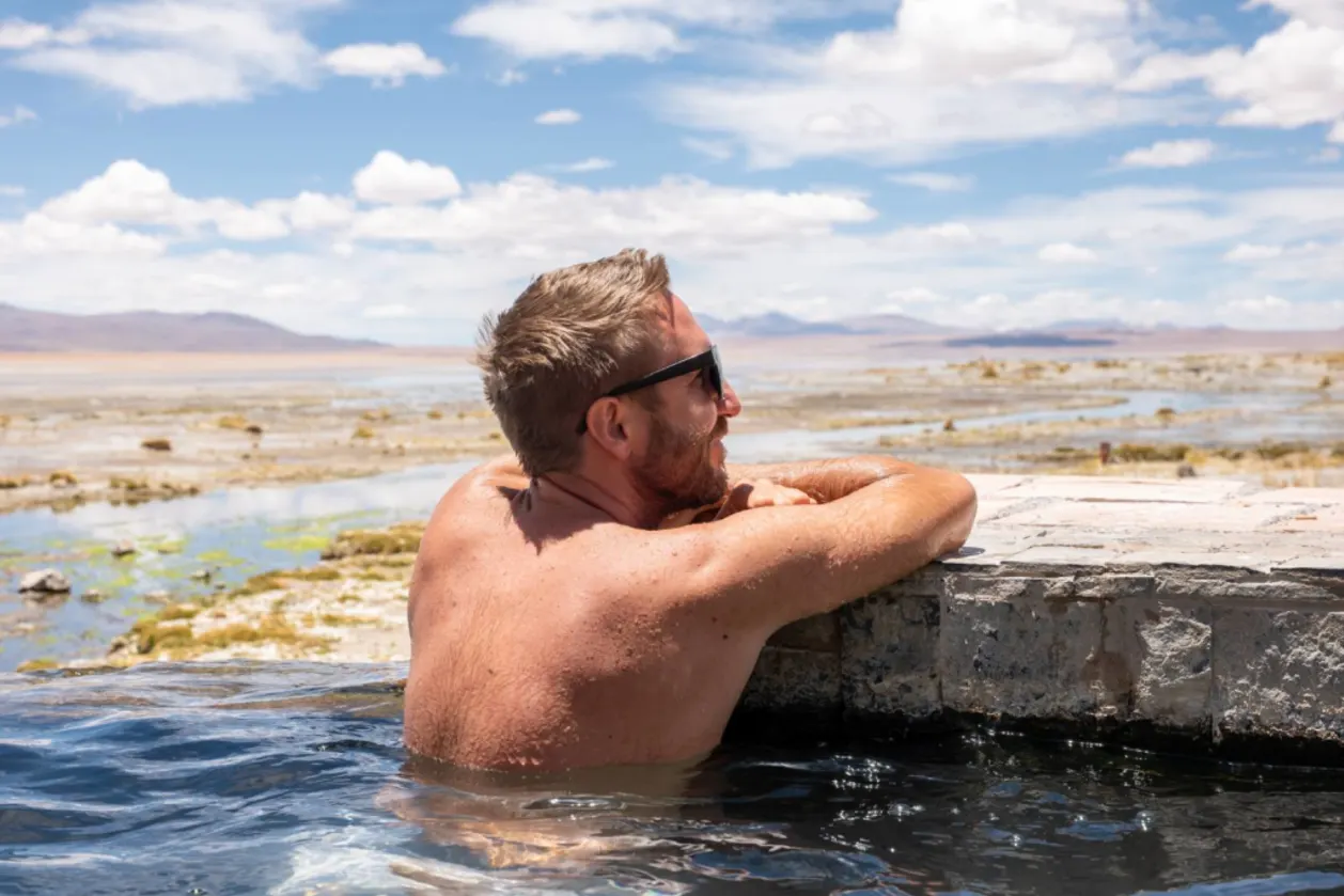Man with sunglasses enjoying a soak in a natural hot spring in Bolivia