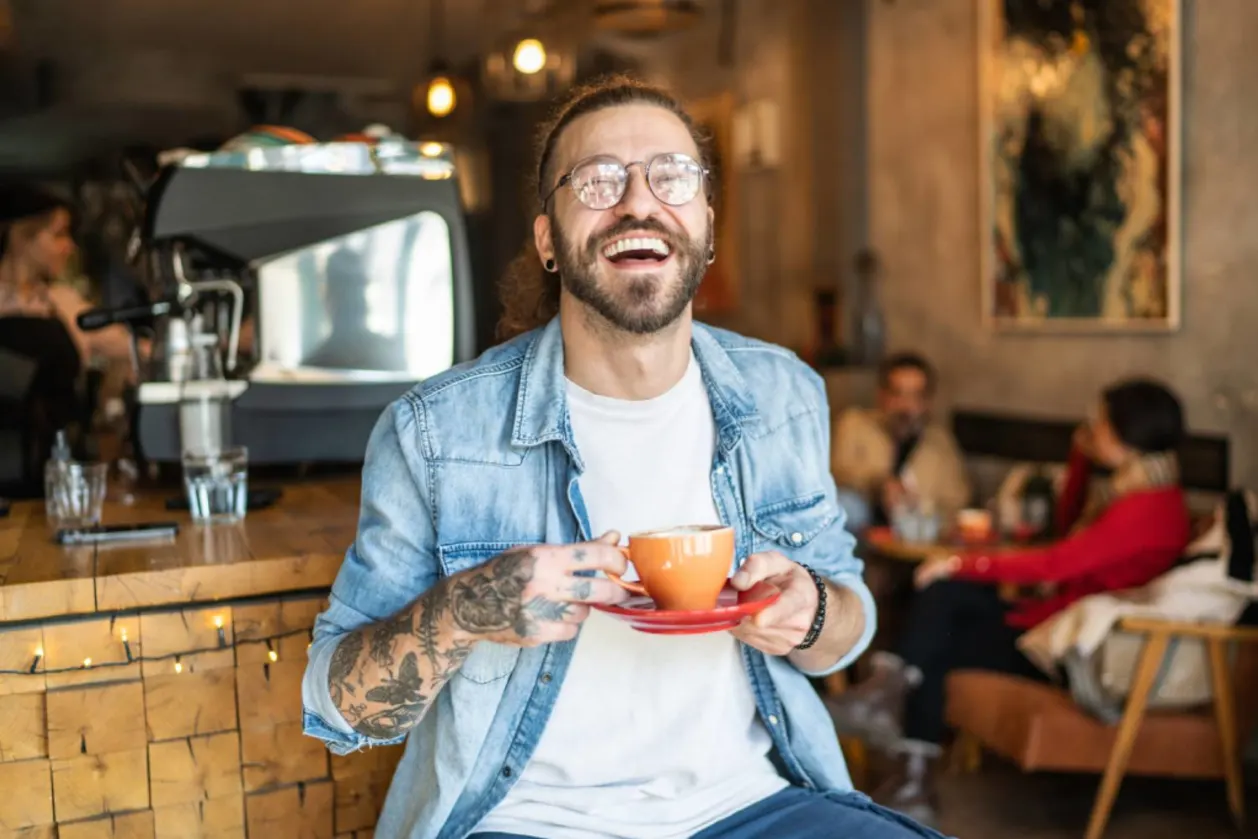 smiling man drinking coffee at café
