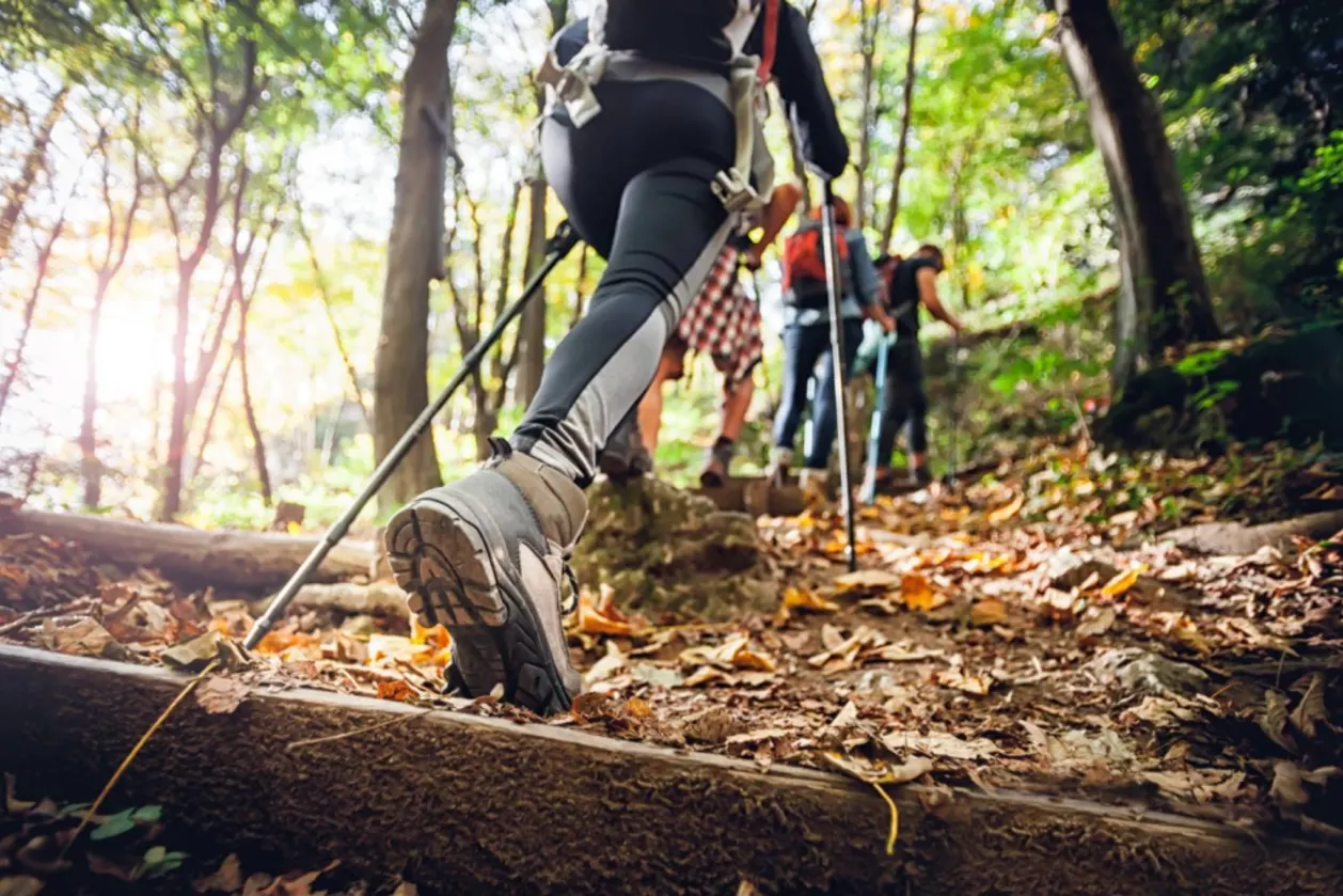 hiker woman with trekking sticks climbs steep mountain-trail-accessibility tips