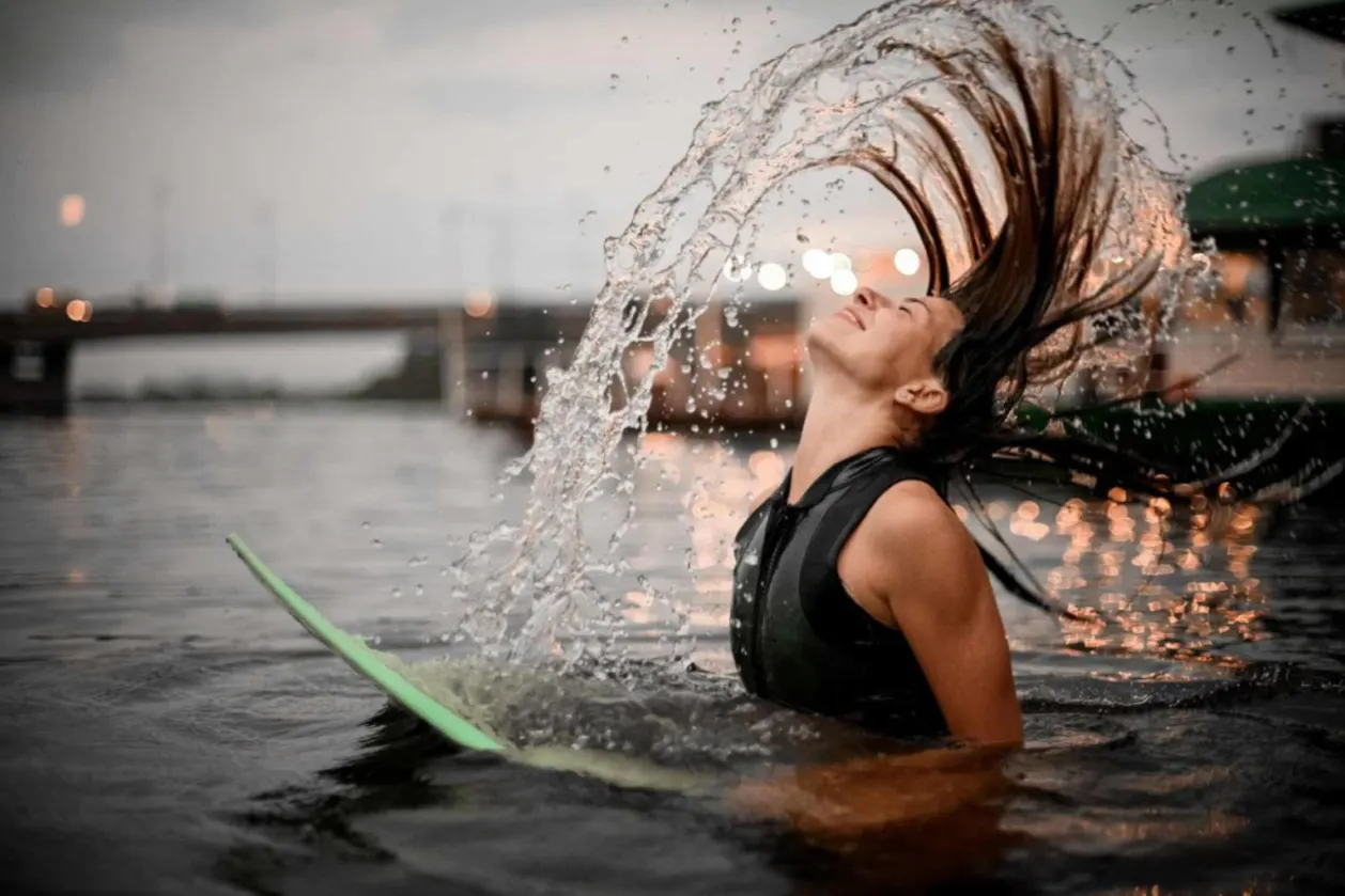 Sporty surfing girl waves her long hair in the water