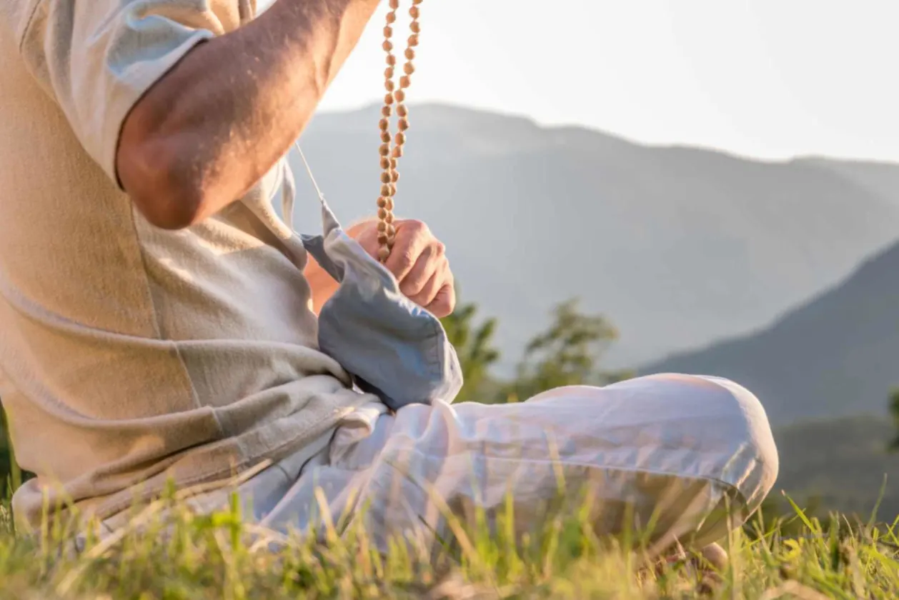 Devoted man using mala beads for meditation and to chant