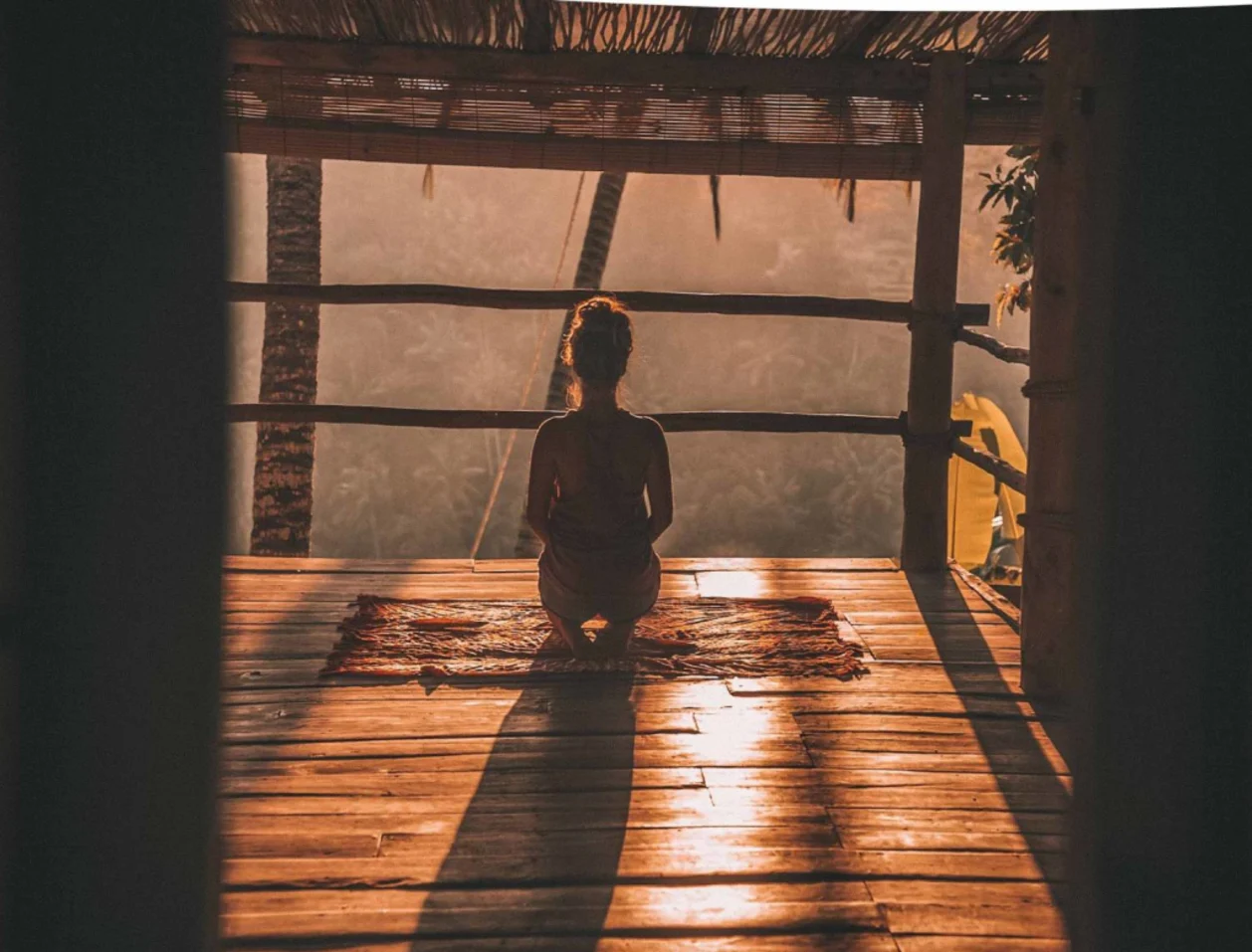 woman meditating in yoga shala with sun peeking in