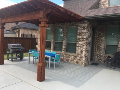 Establishing view of a 14x12 cedar pergola anchored to an existing concrete patio at the Canonica Residence in Arlington, Tarrant County, TX.