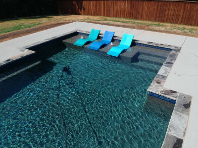 Hero view of a gunite pool with blue water, dual bubblers, and cedar pergola crafted for a Tarrant County outdoor living space in Arlington, TX.