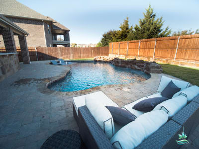 A resort-style outdoor living space at the Bakios residence in Mansfield, TX, featuring a custom pool surrounded by patio furniture designed for multi-generational family gathering and entertainment.