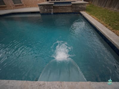 A custom geometric pool with vivid blue water set within a refined outdoor living space at a Colleyville, Tarrant County, TX estate.
