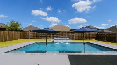 Geometric pool with Burlington Armani Grey travertine coping and cascading sheer descent water feature in a North Richland Hills, TX outdoor living space.
