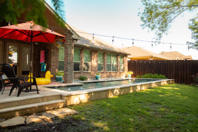 Close-detail view of concrete paver decking alongside stone veneer pool walls accented with mosaic turtle tile inlays at a geometric pool in Arlington, Tarrant County, TX.