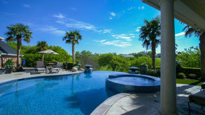 Wide-angle view of a custom pool framed by swaying palm trees in a Fort Worth, Tarrant County, TX outdoor living space.