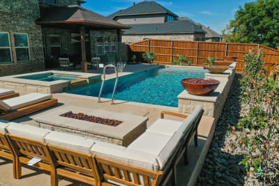 Patio furniture arranged on integrated hardscape decking within a multi-zone outdoor living space at a resort-style retreat in Arlington, Tarrant County, TX.