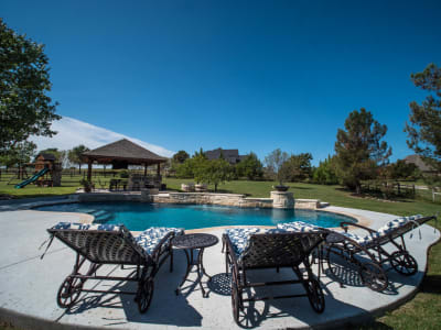 Establishing overview of a classic rectangular pool with Peerless Pebble Regatta Blue finish, Sally Deck, and 18x18 custom pavilion at a Fort Worth, TX residence.