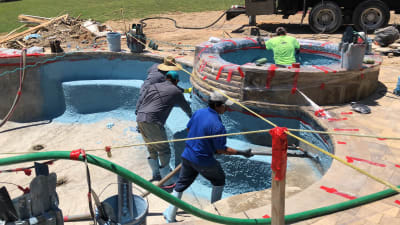 Construction crew placing gunite over reinforced steel framework for a custom raised spa and pool structure at a Fort Worth, TX residence.