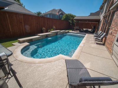 Patio furniture arranged beside a custom pool at a Dallas County outdoor living space crafted by Selah Pools in Grand Prairie, TX.