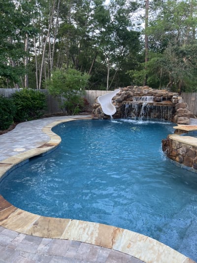 Luxury swimming pool with slide, waterfall, stone facade spa, and deck at the Colon Residence in Santa Rosa Beach, FL.
