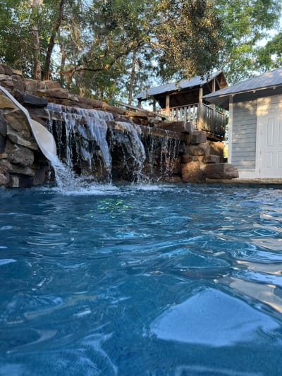 Luxury swimming pool with cascading waterfalls and blue tile finish at the Colon Residence in Santa Rosa Beach, FL.