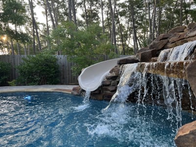 Backyard pool with water features and outdoor kitchen at the Colon Residence in Santa Rosa Beach, FL.