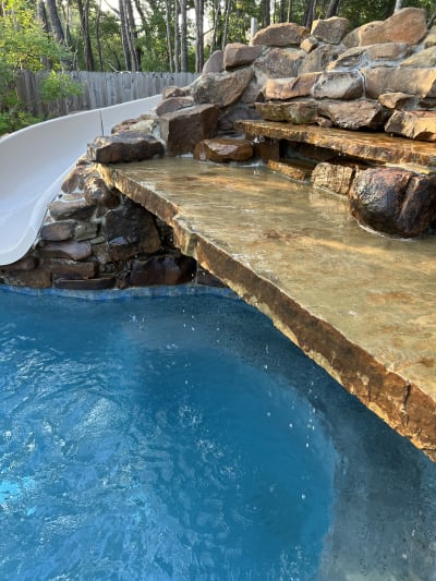 Outdoor water feature with tanning ledge and raised beam element at the Colon Residence pool in Santa Rosa Beach, FL.