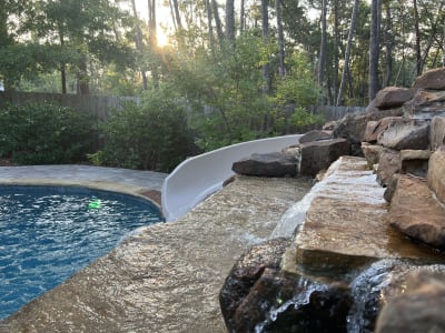 Luxury outdoor pool with spa, water feature, and fire pit at the Colon Residence in Santa Rosa Beach, FL, featuring travertine and marble finishes.