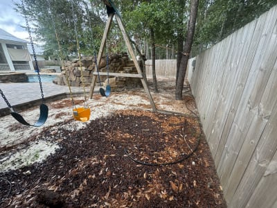 Wide view of a freeform pool with custom rock grotto, GRS10 slide, and Oklahoma Stone coping set within a naturalistic outdoor living space in Santa Rosa Beach, FL.