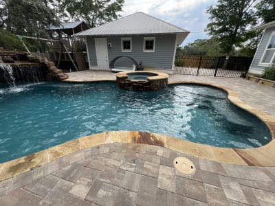 Backyard swimming pool with circular spa and deck jets beside a fire pit patio at the Colon Residence in Santa Rosa Beach, FL.