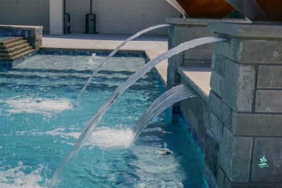 Close detail of crystal-clear pool water meeting stone coping and tile finish, showcasing the advanced automated filtration system at the Carter Residence in Godley, TX.