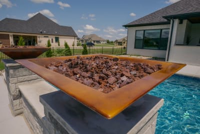 Close-detail view of natural stone and wood pool equipment surroundings at the Carter Residence in Godley, Johnson County, TX, where advanced automated systems maintain crystal-clear water without manual intervention.