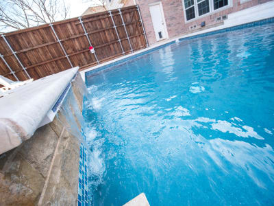 Close detail of a blue pool water surface reflecting the Texas sky at a custom outdoor living space in Irving, Dallas County, TX.