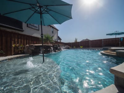 A custom residential pool with a bold blue cantilever umbrella anchoring the outdoor living space at the Golovich family estate in Mansfield, Tarrant County, TX.