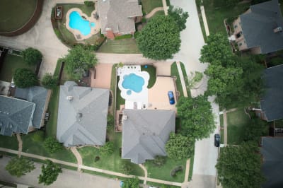 Stunning aerial perspective showcases the elegant proportions of this custom pool featuring Peerless Pebble Blue finish and premium travertine coping in Irving.