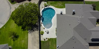 Close detail of a classic rectangular pool in Mansfield, Tarrant County, TX, showcasing Peerless Pebble French Gray interior, Mastertile Abyss Series tile, Pre-Cast Eased Edge tan coping, and Cool Adobe Bluff decking with ash gray speckling.