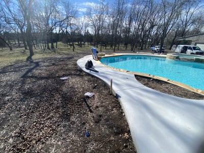 Deck-level view of a freeform pool with custom spa and tanning ledge, showcasing the smooth composite board bench and walkway in Anna, TX.
