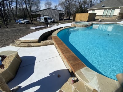 Custom freeform pool with stone fire pit and EcoLuxe beach in Anna, Texas outdoor living space showcases a tanning ledge, bubblers, and lighting